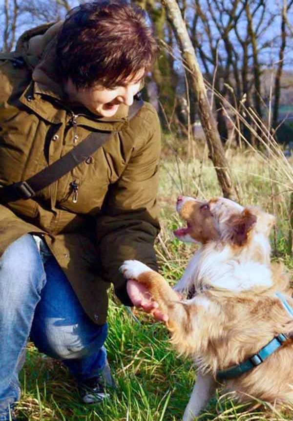 Hund legt Pfote in Hand von Hundetrainerin Margarete Yen