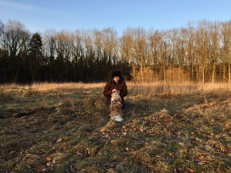 Margarete Yen mit Hund auf trockenem Gras bei Sonnenuntergang